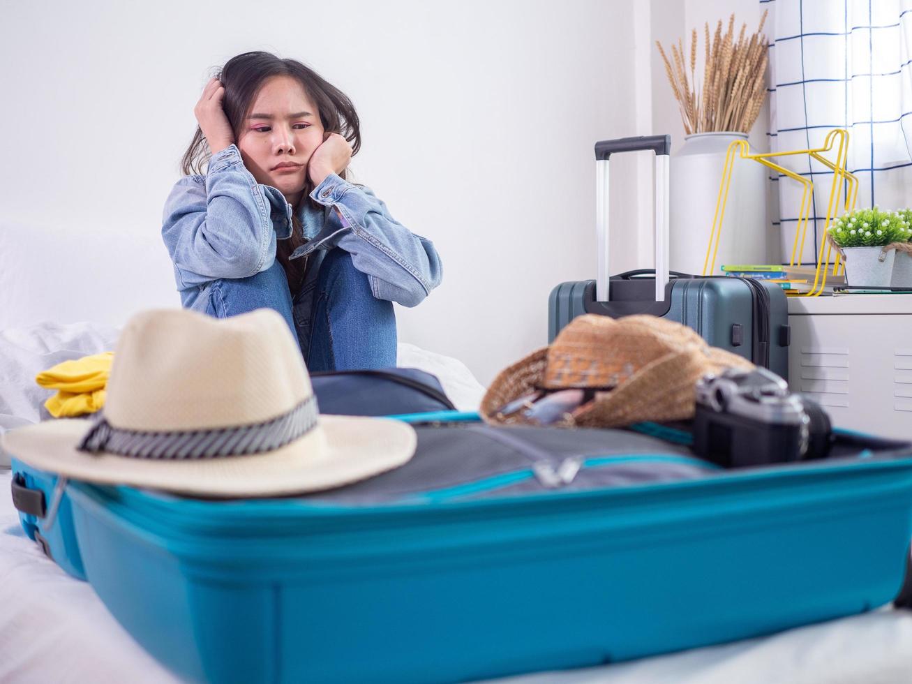 las mujeres asiáticas están sentadas de un humor triste después de empacar una bolsa de ropa y dudan en pasar el rato por temor a la situación de infección. 2019-ncov se está extendiendo por todo el mundo. plaga mortal del mundo foto