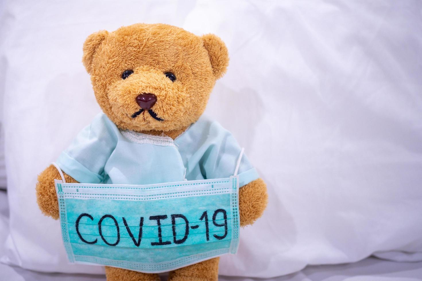 oso de peluche enfermo con máscara escribe covid-19. la situación de la infección por el virus 2019-ncov en wuhan se está extendiendo por todo el mundo. plaga mortal del mundo. concepto usar máscara para proteger el coronavirus foto