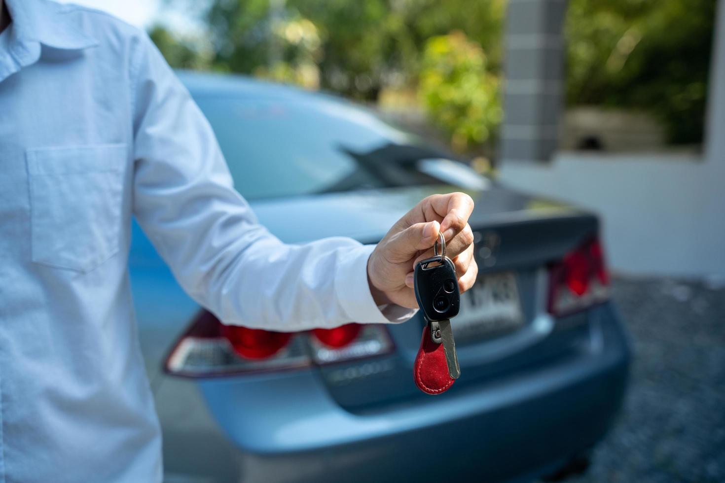 alquiler, compra, venta de coches. empleado de una empresa de alquiler de coches turísticos presenta las llaves del coche con una prueba de conducción. buen servicio antes de acordar un contrato de arrendamiento o compra. foto