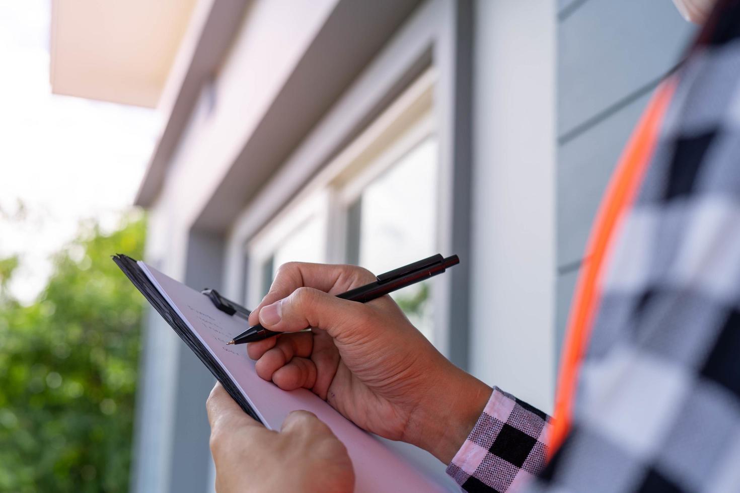 el inspector o ingeniero está inspeccionando la construcción y el aseguramiento de la calidad de la nueva casa usando una lista de verificación. ingenieros o arquitectos o contratistas trabajan para construir la casa antes de entregársela al propietario foto