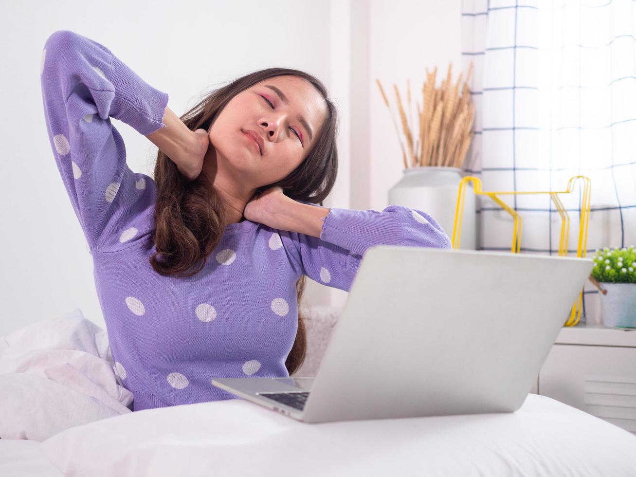 las mujeres asiáticas tienen dolor en el cuello y los hombros, similar al músculo inflamado después de sentarse usando una computadora en la cama. foto