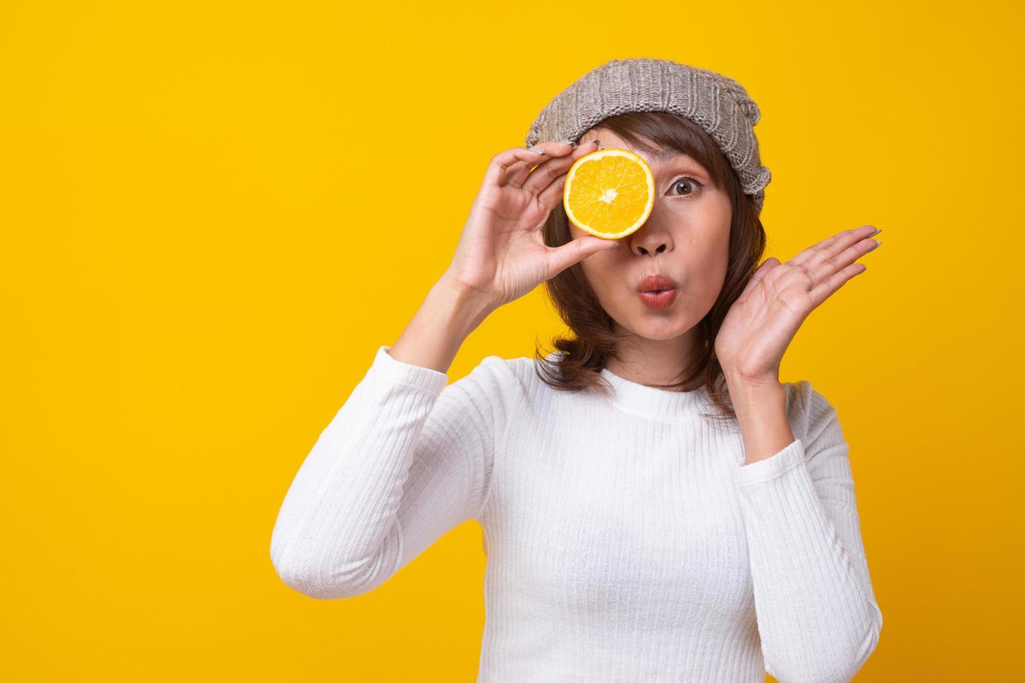 The girl in the white shirt holding an orange cut in the hand closed the eyes and kissing. she face  bright. The concept of fruit for health, skin care and diet. photo