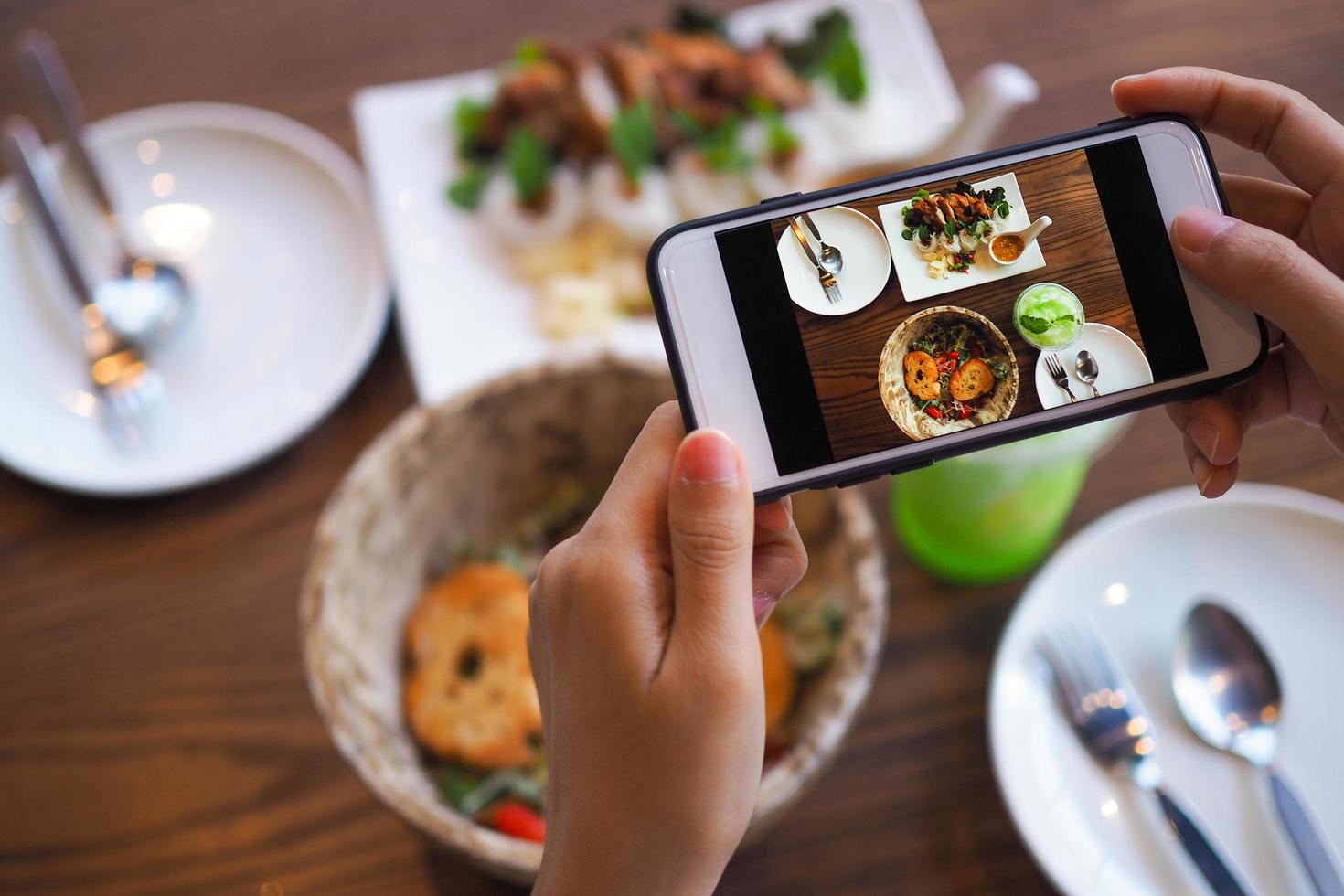 The hand of a woman take pictures of food made by herself. Food sellers take photo with a smartphone to post on the online food ordering website.