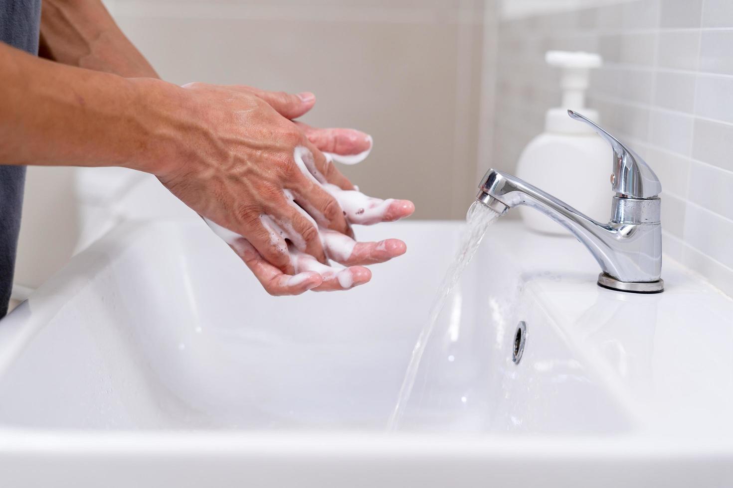 Person hands wash with soap bubbles and rinse with clean water to prevent and stop the spread of germs, virus or covid-19. Good health and good hygiene photo