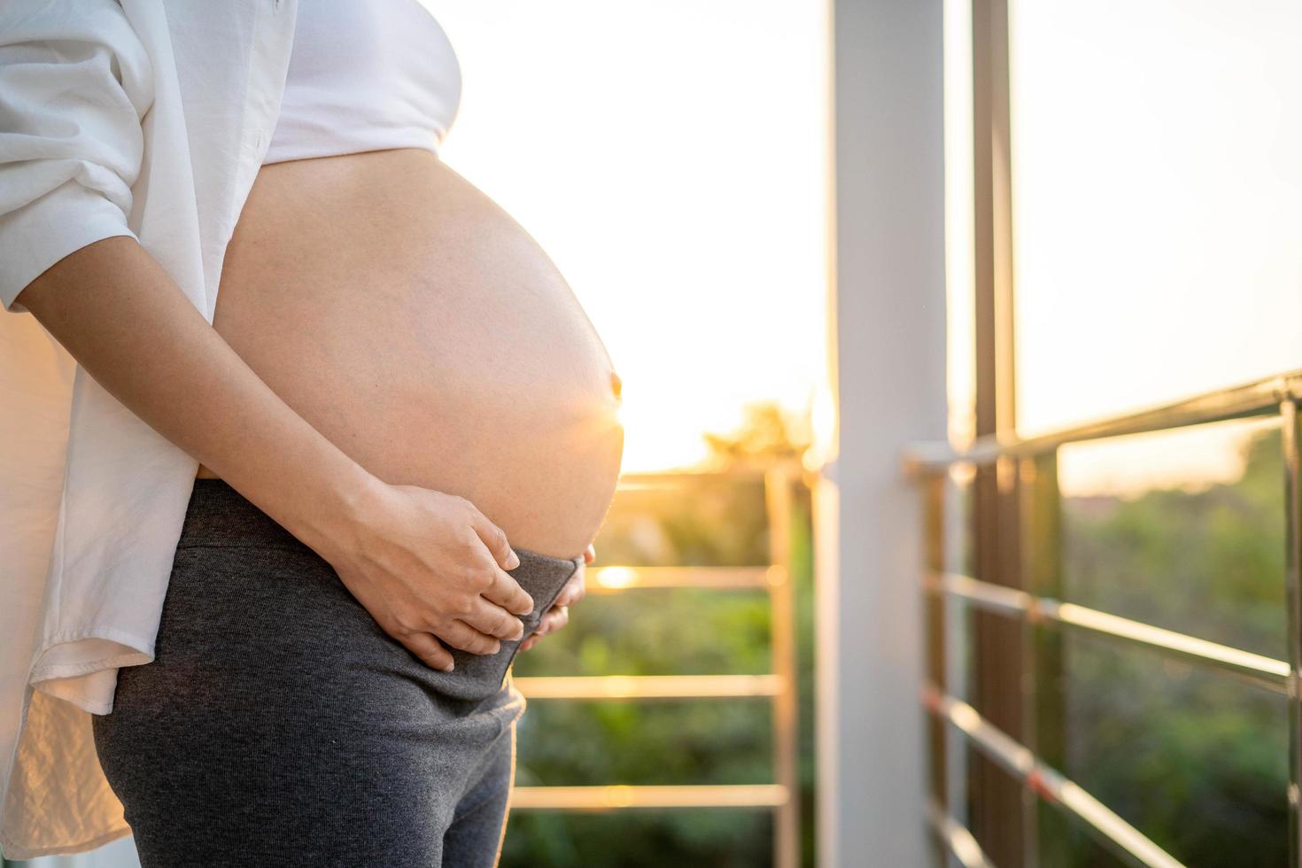 An 8 month pregnant woman gently touches her belly at sunset. Mom with baby in abbomen so happy time while she is pregnant. photo