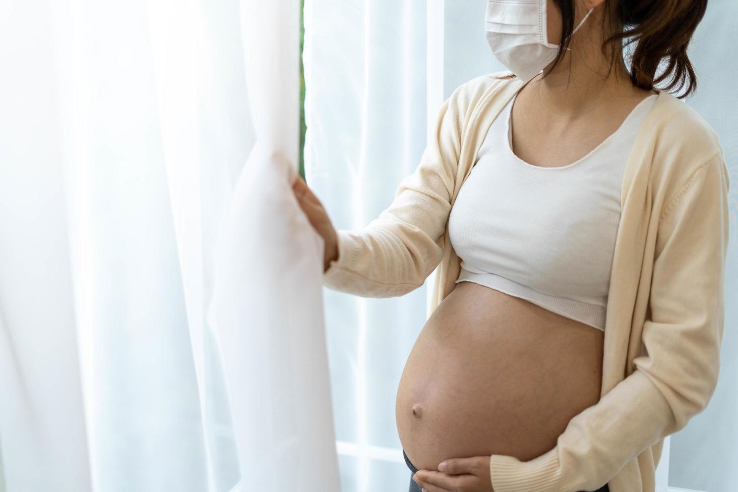 The woman is 28 weeks pregnant, wearing a face mask to prevent viruses and pollen or pm2.5 dust. photo