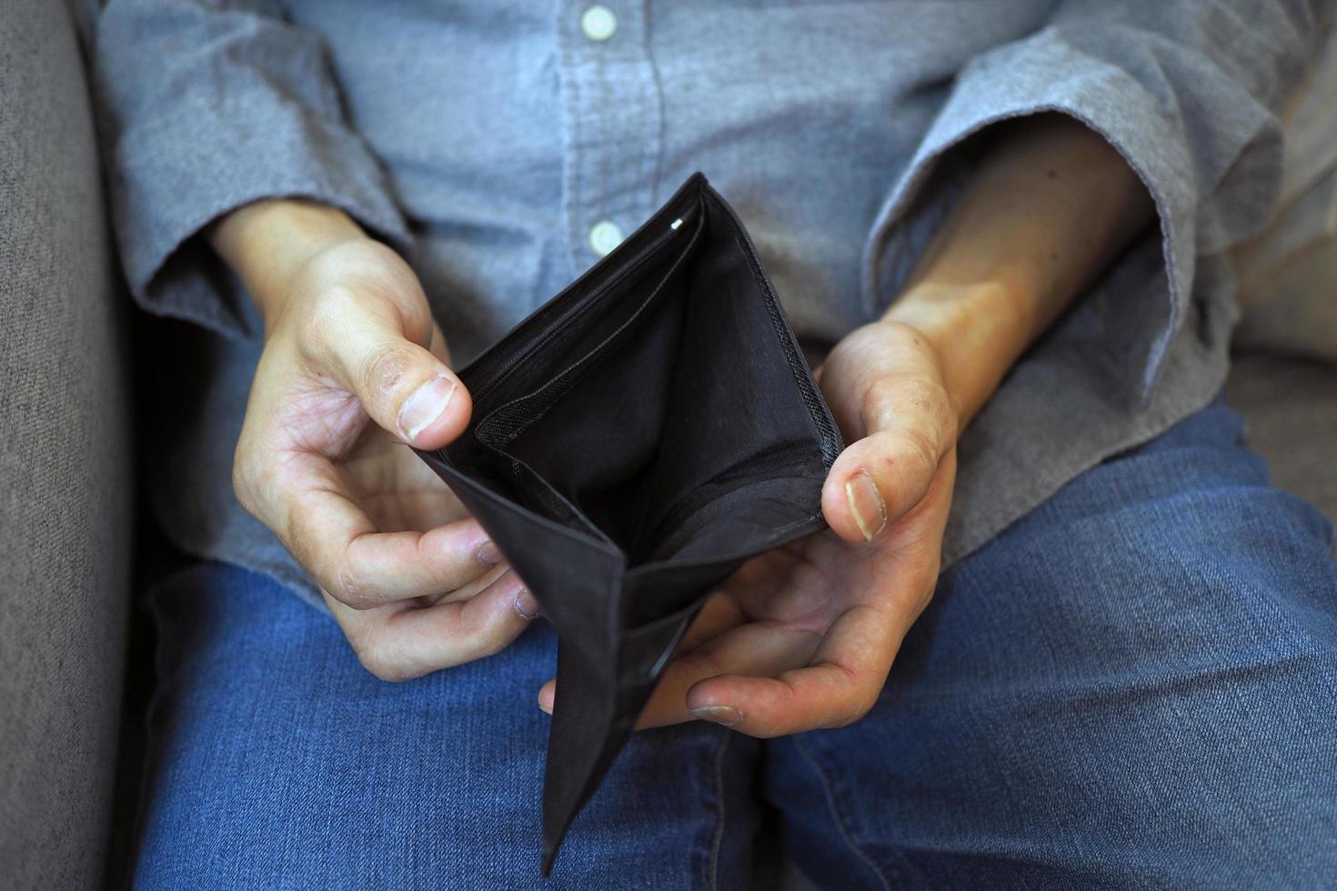 las manos del hombre abren el monedero vacío. pobreza, endeudamiento y quiebra en el pago de facturas y tarjetas de crédito. concepto roto foto