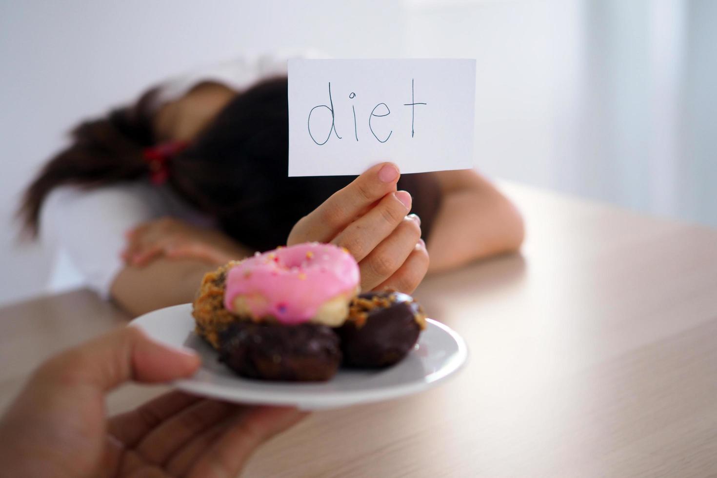 A woman holding a sign that says that Diet is for the person who sends the dish to the donut. photo