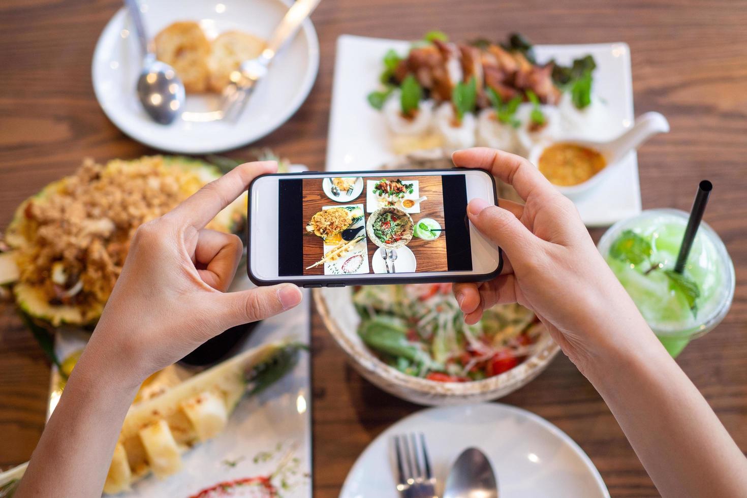 woman using a mobile camera take pictures of food placed on the table in house. After calling to order food online from home. Stay at home and shopping online during the spread of the covid-19 virus. photo