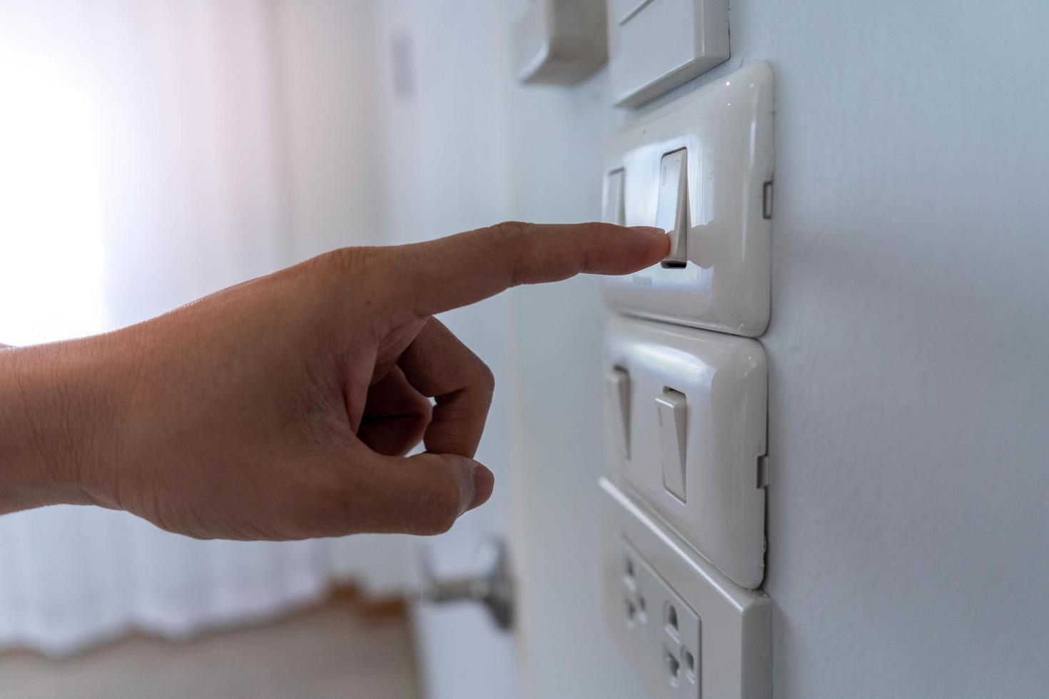 Ahorre electricidad, ahorro de energía y protección del medio ambiente. el dedo del hombre presiona el botón para apagar la luz. uso economico de la electricidad foto