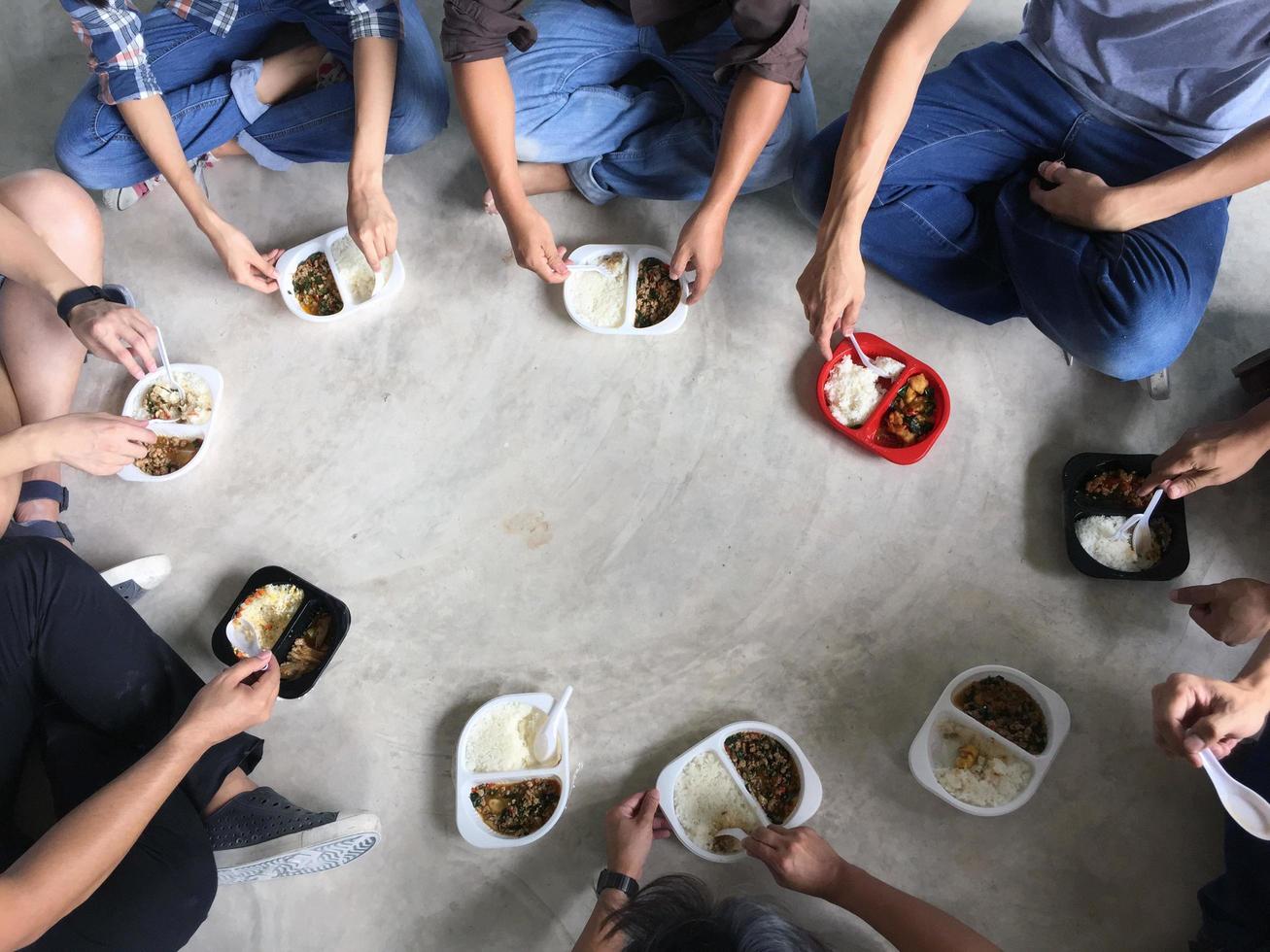 el grupo de empleados se sentó en círculo, comiendo juntos una caja de comida rápida. foto