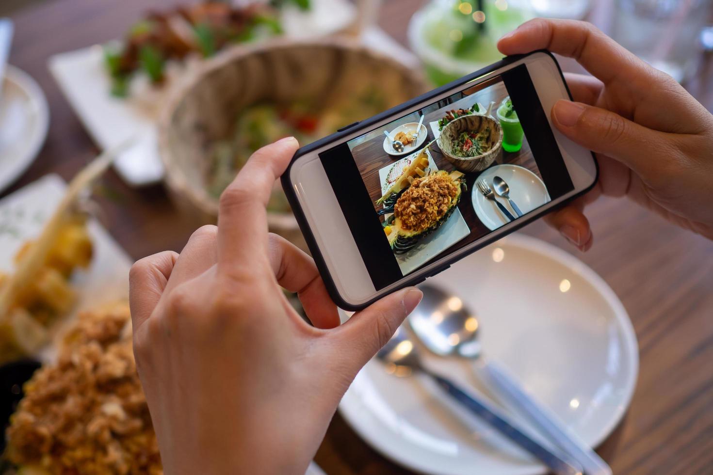 Woman using mobile phone to take pictures of food on the table. Taken on mobile and put on social networks. photo