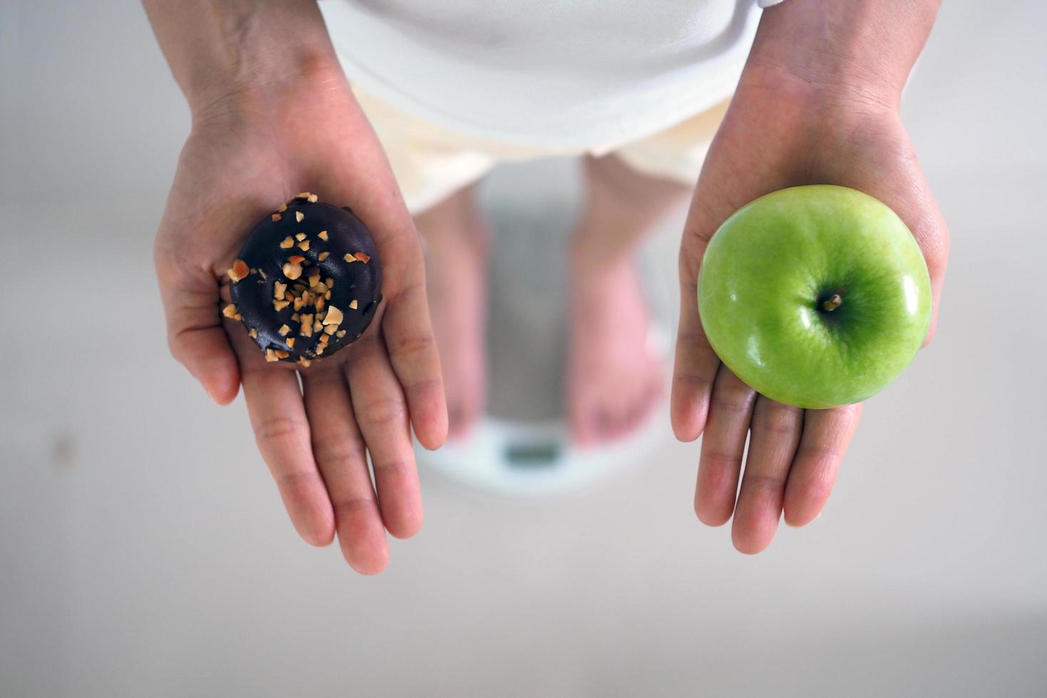 Women are weighing heavily. Choose between donuts and apples. photo