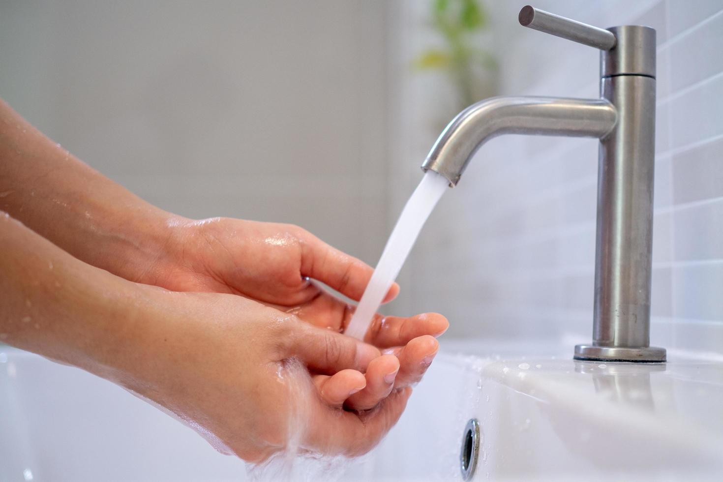 Women turn on the water to wash their hands in the bathroom. Frequent hand washing to help clean, reduce the accumulation of bacteria and viruses. photo