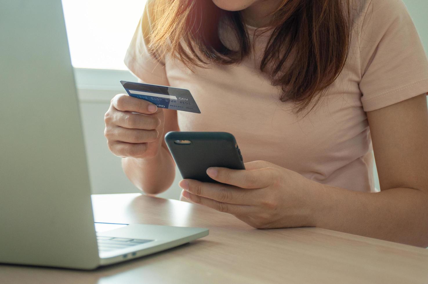 una mujer joven usa una tarjeta de crédito para comprar pagos en línea en una aplicación de computadora portátil o en un sitio web. concepto de comercio electrónico y compras en línea. quédate en casa y compra productos en línea. foto