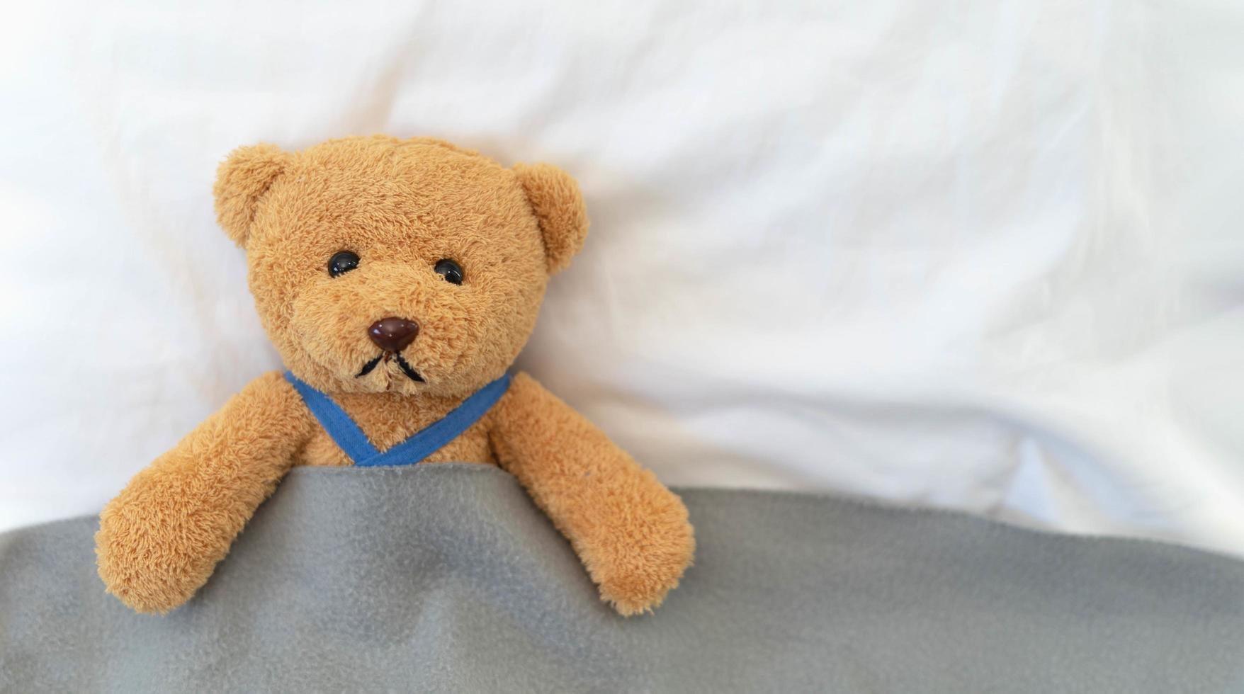 A sad teddy bear lies sick in bed with disappointment and discouragement photo