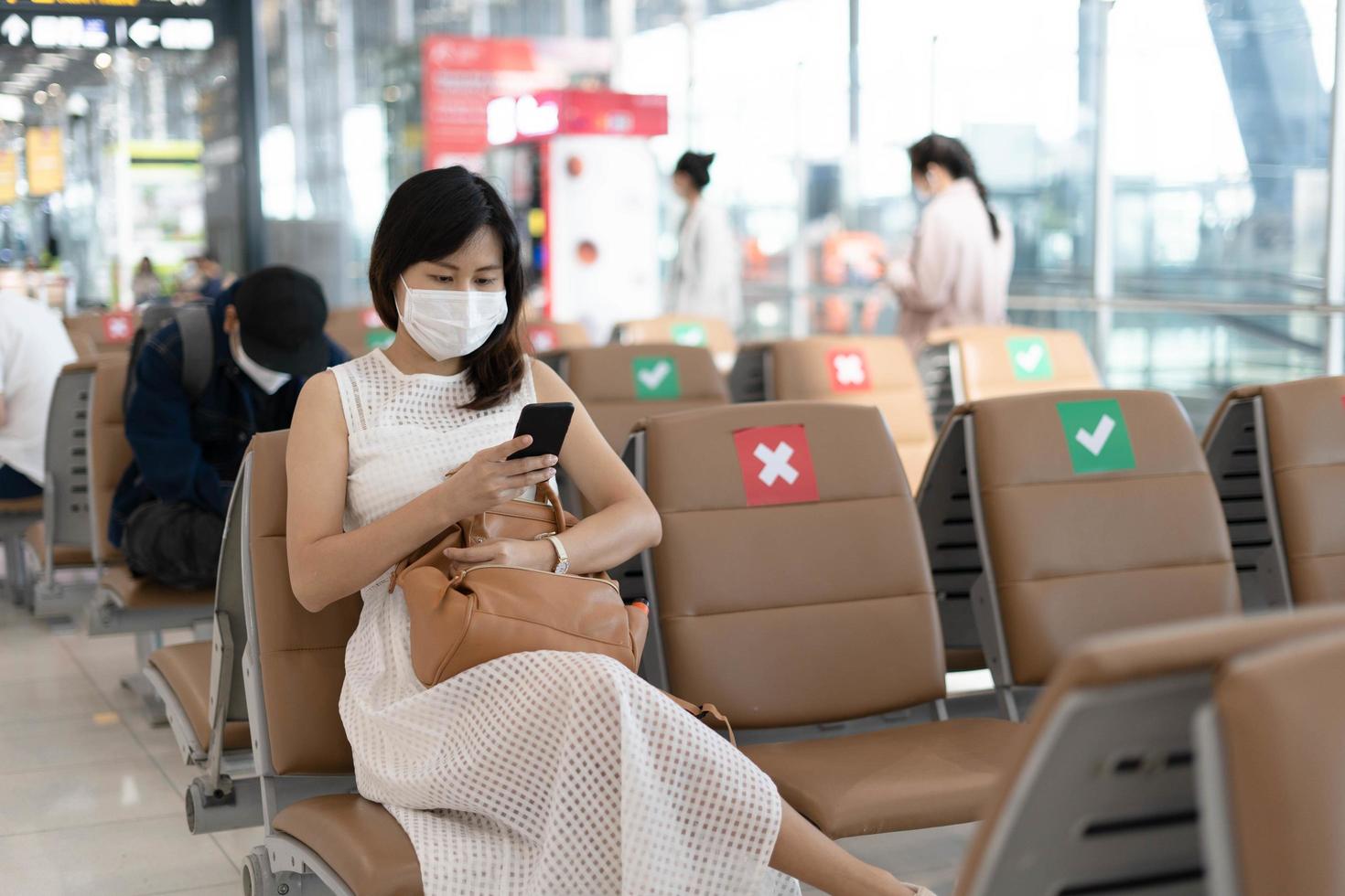 Asian women wear a mask and sit between chairs to reduce the spread of the coronavirus. Tourists wait to get on planes during the covid-19 outbreak. photo