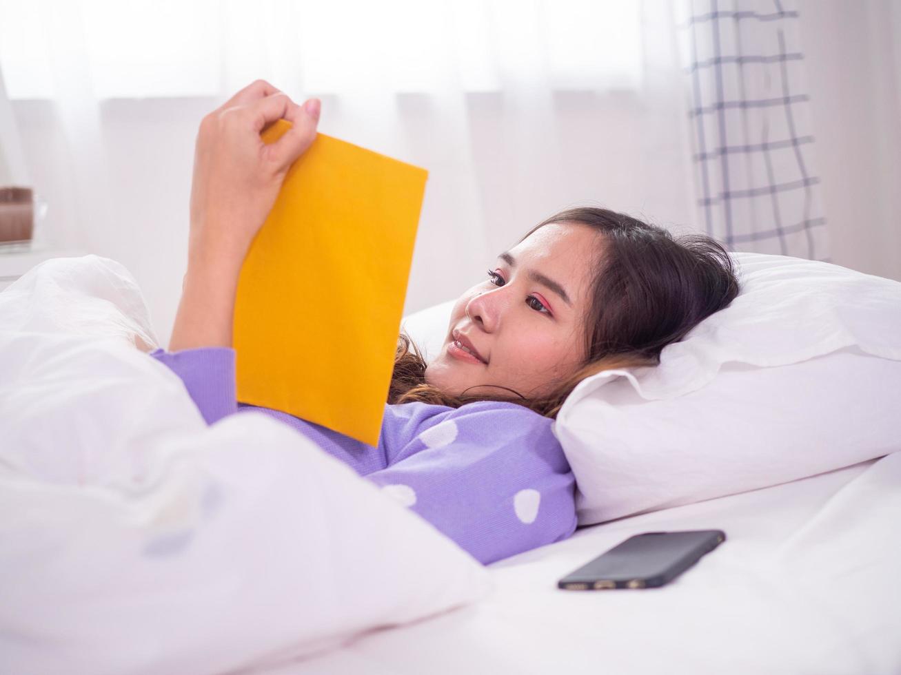 una mujer leyendo en la cama en una habitación con una postura relajada descansando de vacaciones. foto