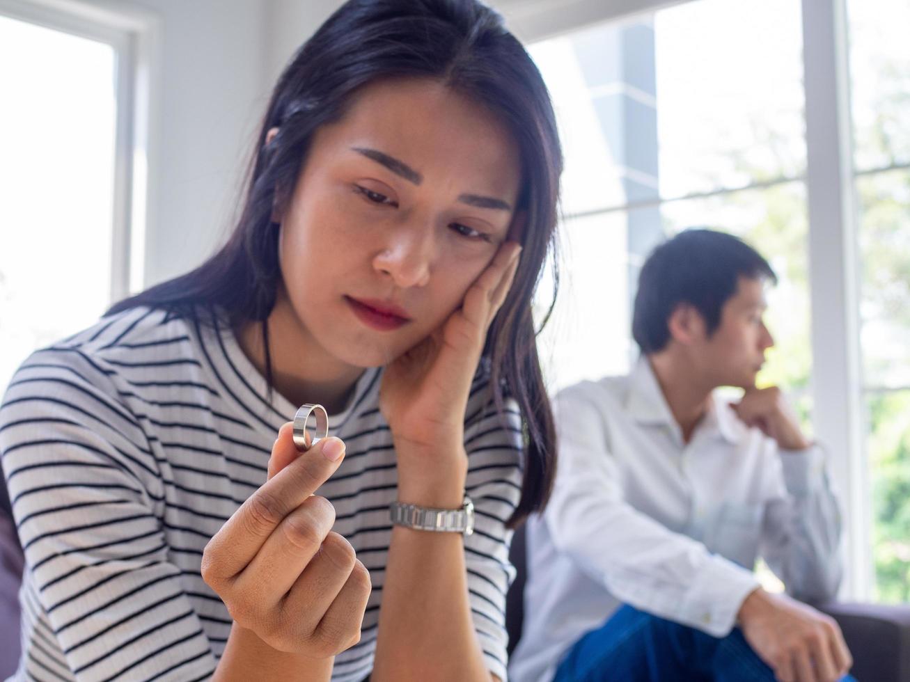 Asian woman sat with the wedding ring, thinking seriously sad and sad after arguing with her husband. The problems of lovers must separate. Family issues, divorce, washing, causing loss photo