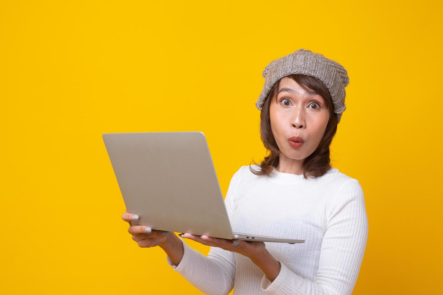 Female is surprised with the story seen in the notebook. Holding a notebook, stunned with what he saw standing on a yellow background. photo