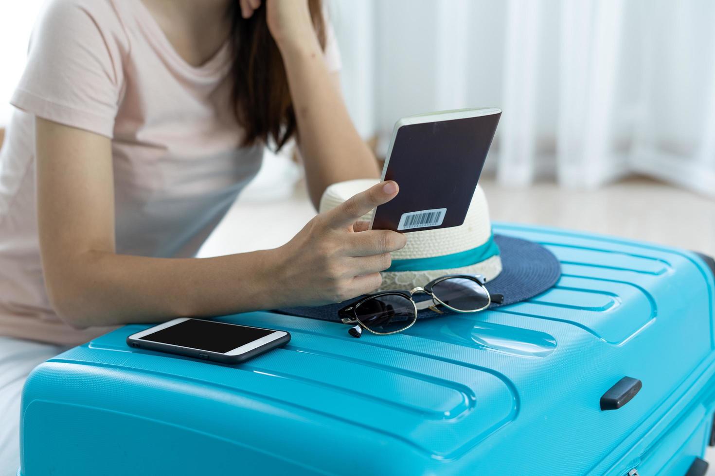 Asian women are sitting looking at their passports and smiling happily. Woman packing suitcase to prepare to travel on vacation.Travel and prepare a clothing bag concept. photo