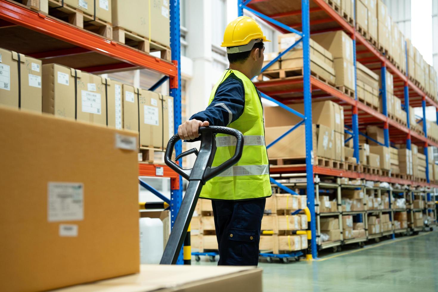 Warehouse worker pull pallet truck after inspects goods in inventory and check stock product. Transport logistic business shipping and delivery to customers through a freight forwarding company. photo