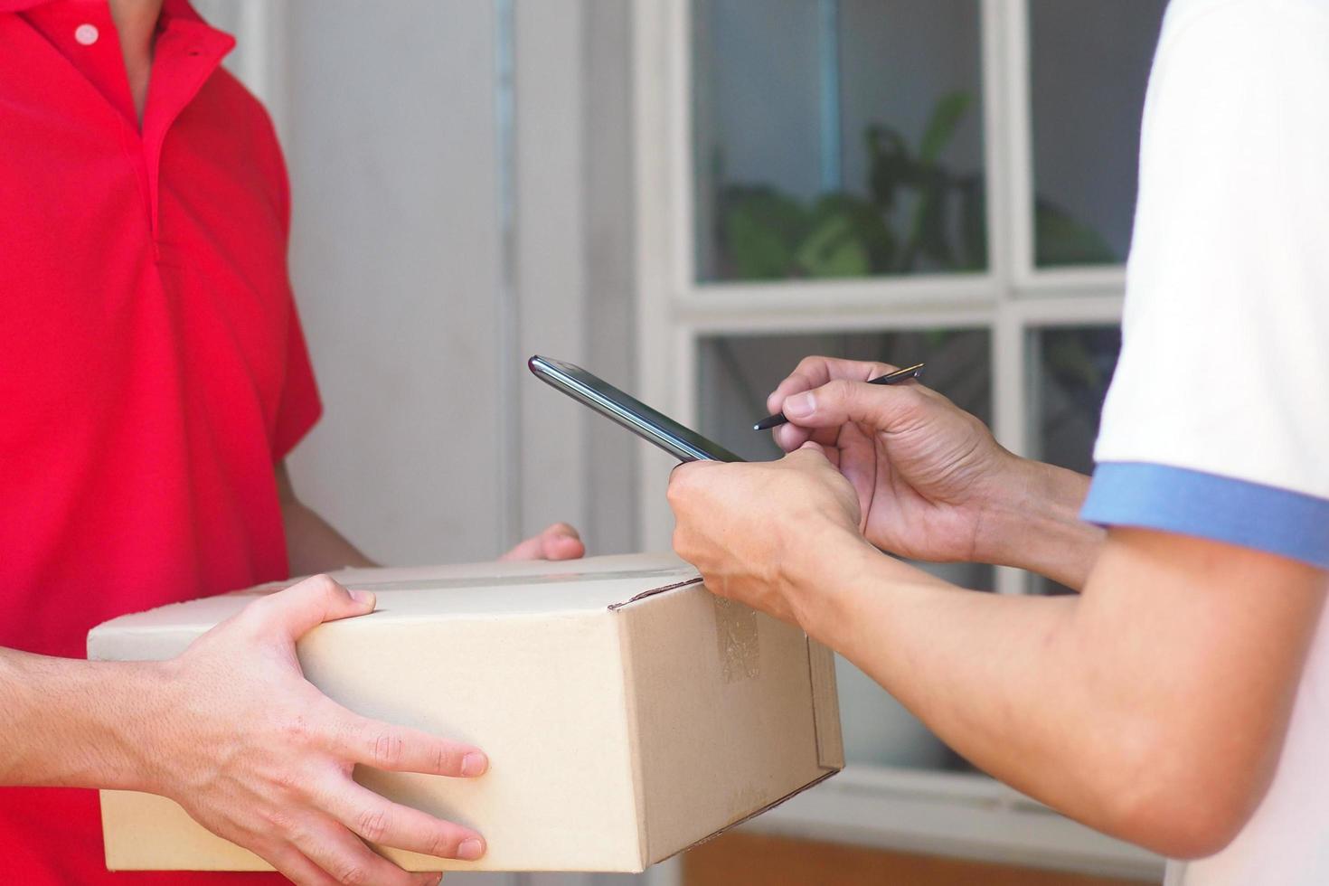 manos firmadas para recibir paquetes de compras en línea el joven envió el teléfono inteligente y la caja foto