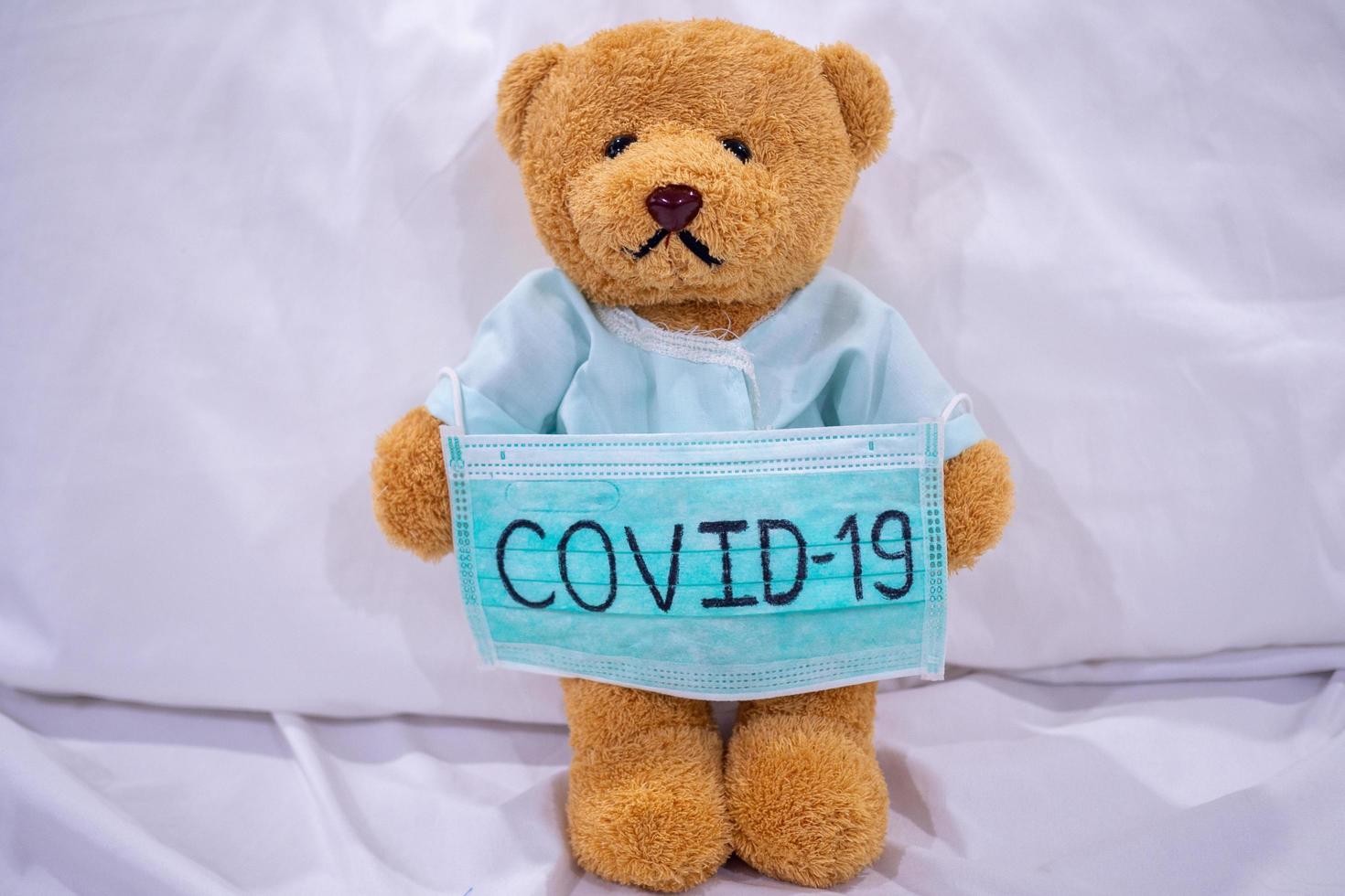 oso de peluche enfermo con máscara escribe covid-19. la situación de la infección por el virus 2019-ncov en wuhan se está extendiendo por todo el mundo. plaga mortal del mundo. concepto usar máscara para proteger el coronavirus foto