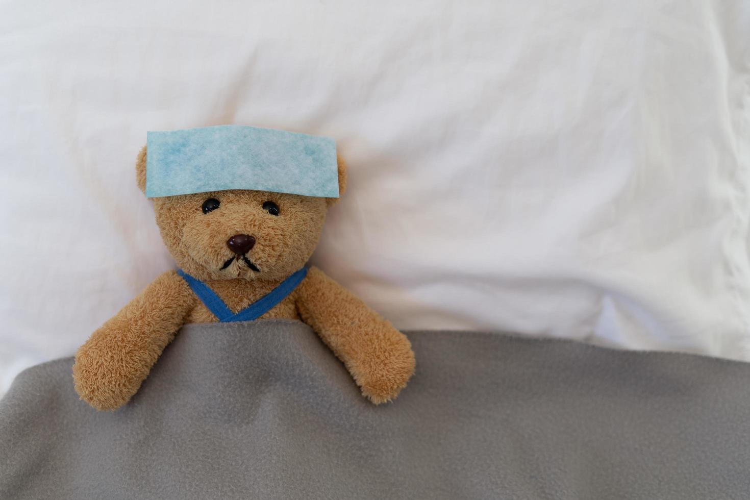 A sad teddy bear lies sick in bed with disappointment and discouragement photo