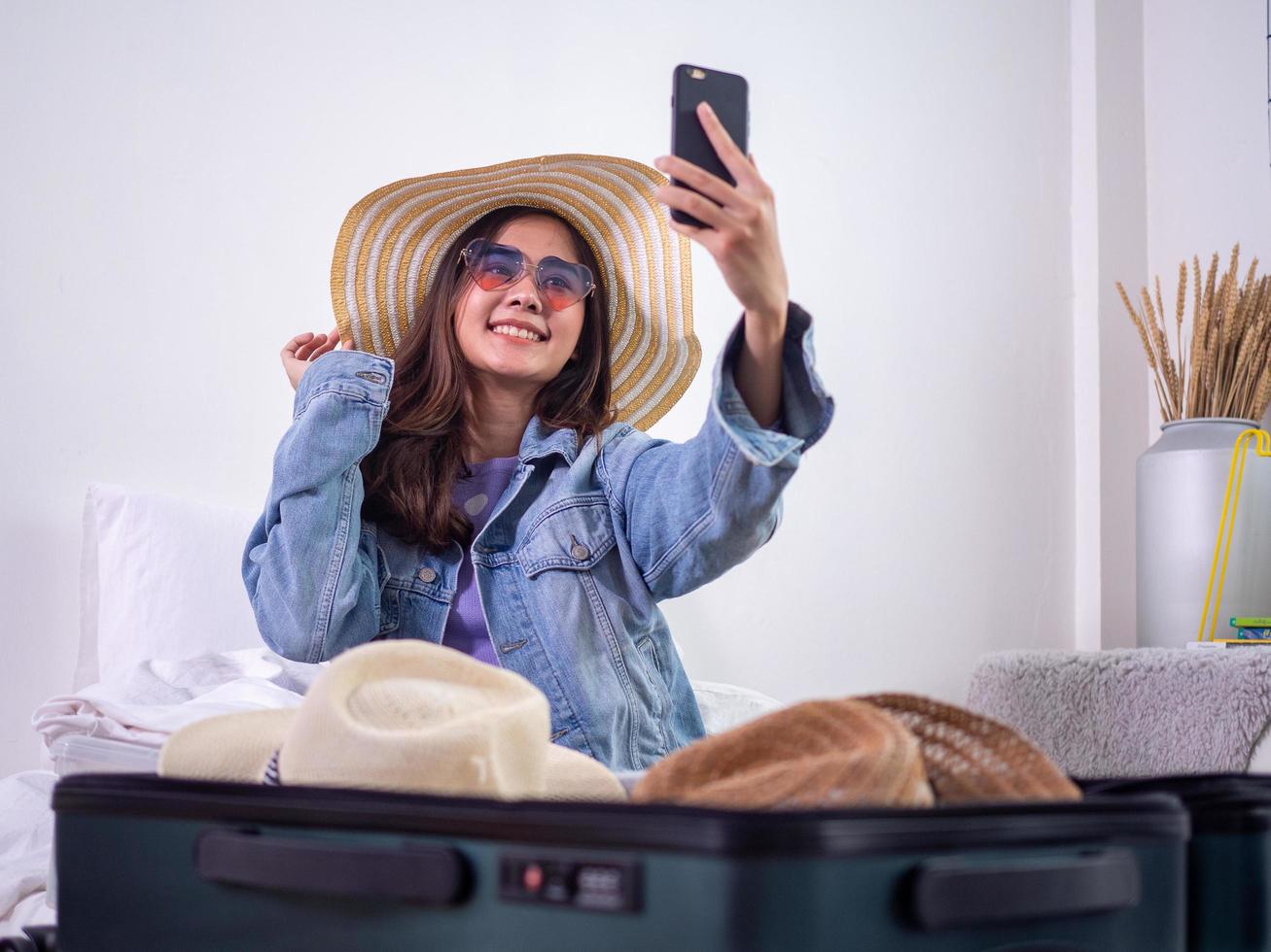 The girls are excited about choosing a hat to wear on vacation. Sitting and collecting clothes in bags to prepare to travel happily. photo