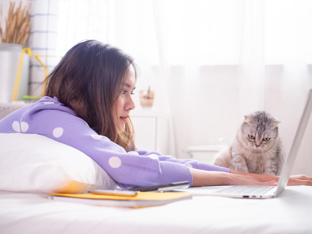 A beautiful woman smiled and played with cats on the bed in the house. photo