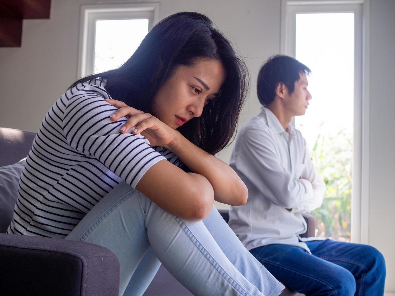 pareja triste que no se habla después de la pelea. Mujer disgustada y pensativa que se siente ofendida y pensando en problemas en las relaciones, hombre disgustado sentado en el fondo. foto