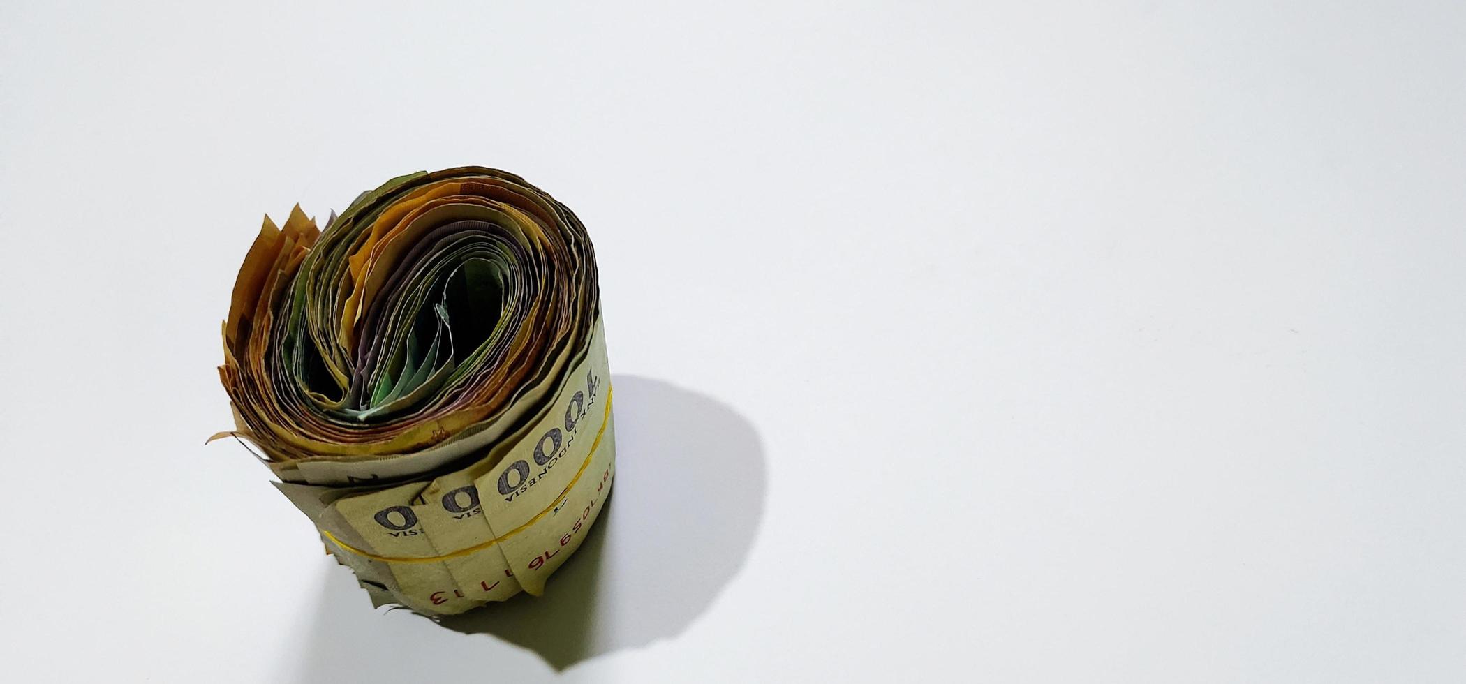 Rubber roll filled with Indonesian banknotes of various denominations and colors isolated on a white background photo