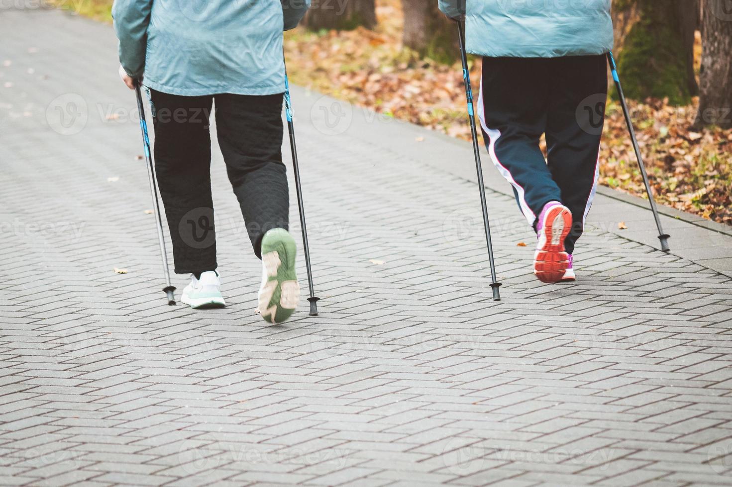 Nordic walking in autumn, senior women exercising outdoors photo