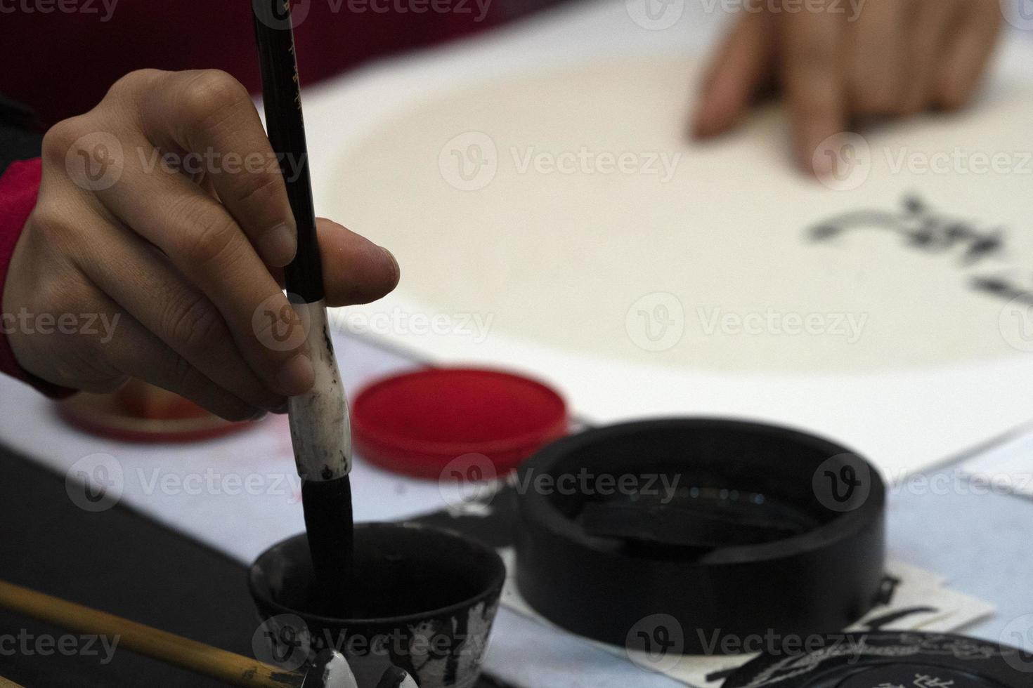japanese woman writing ideograms with brush photo