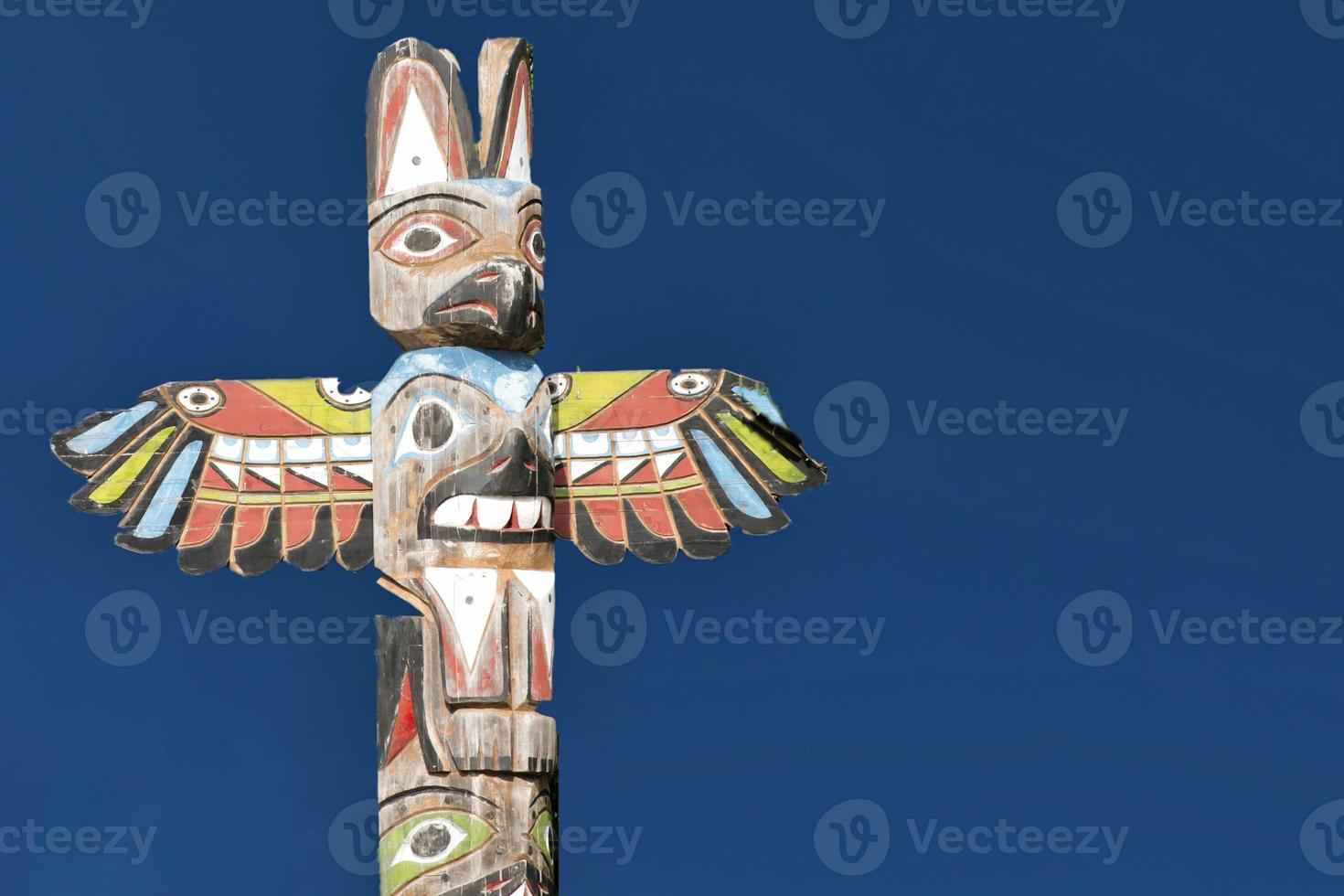 A totem wood pole in the blue background photo