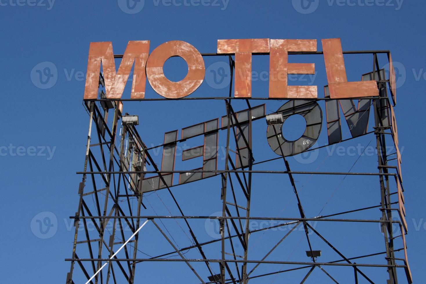 motel rusted sign on blue sky background photo