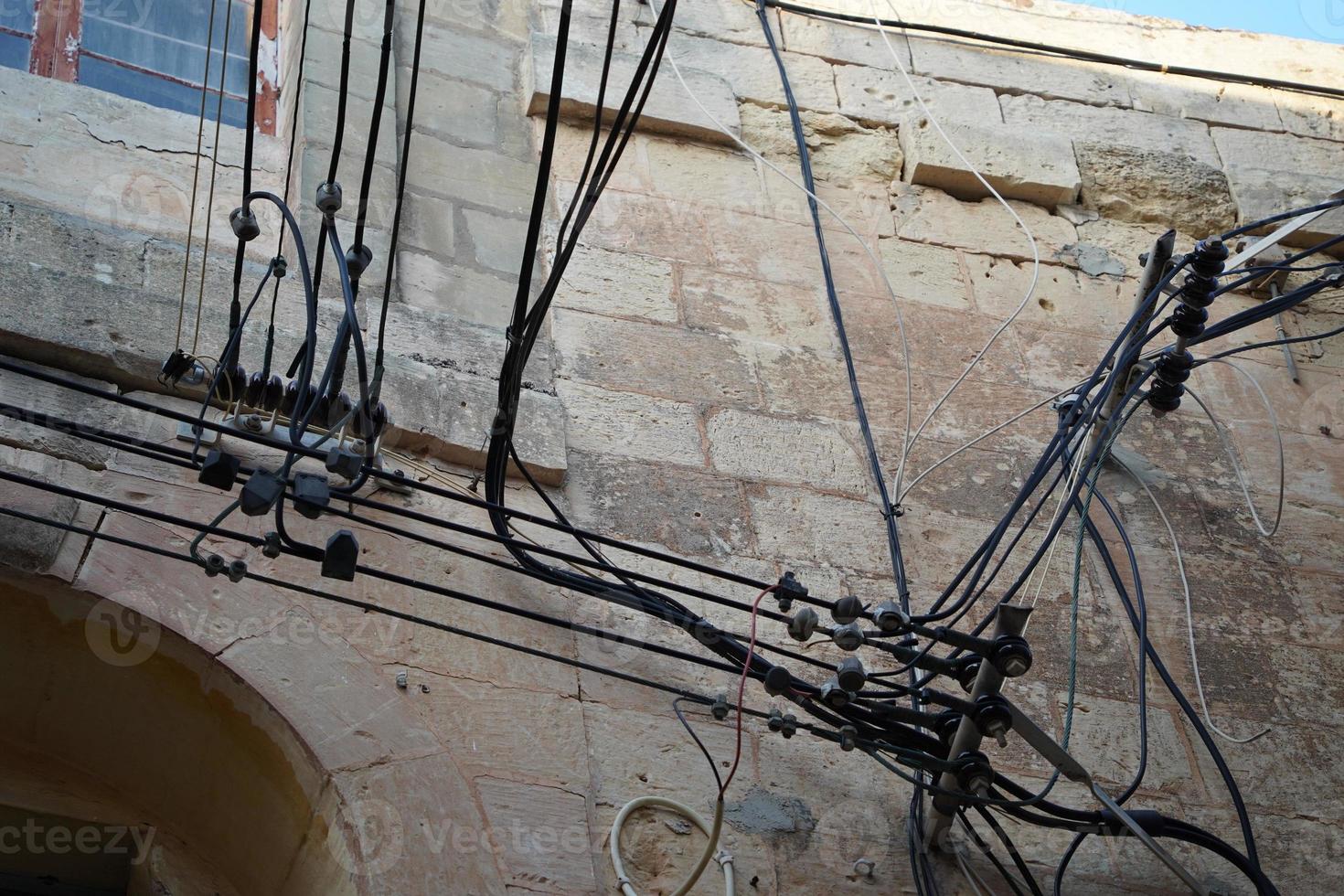 cables eléctricos de malta colgando del edificio foto