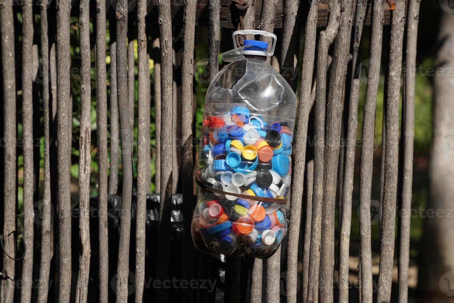 Bottles cups to recycle. Big plastic gallon full of colored bottles cups sunny day. photo