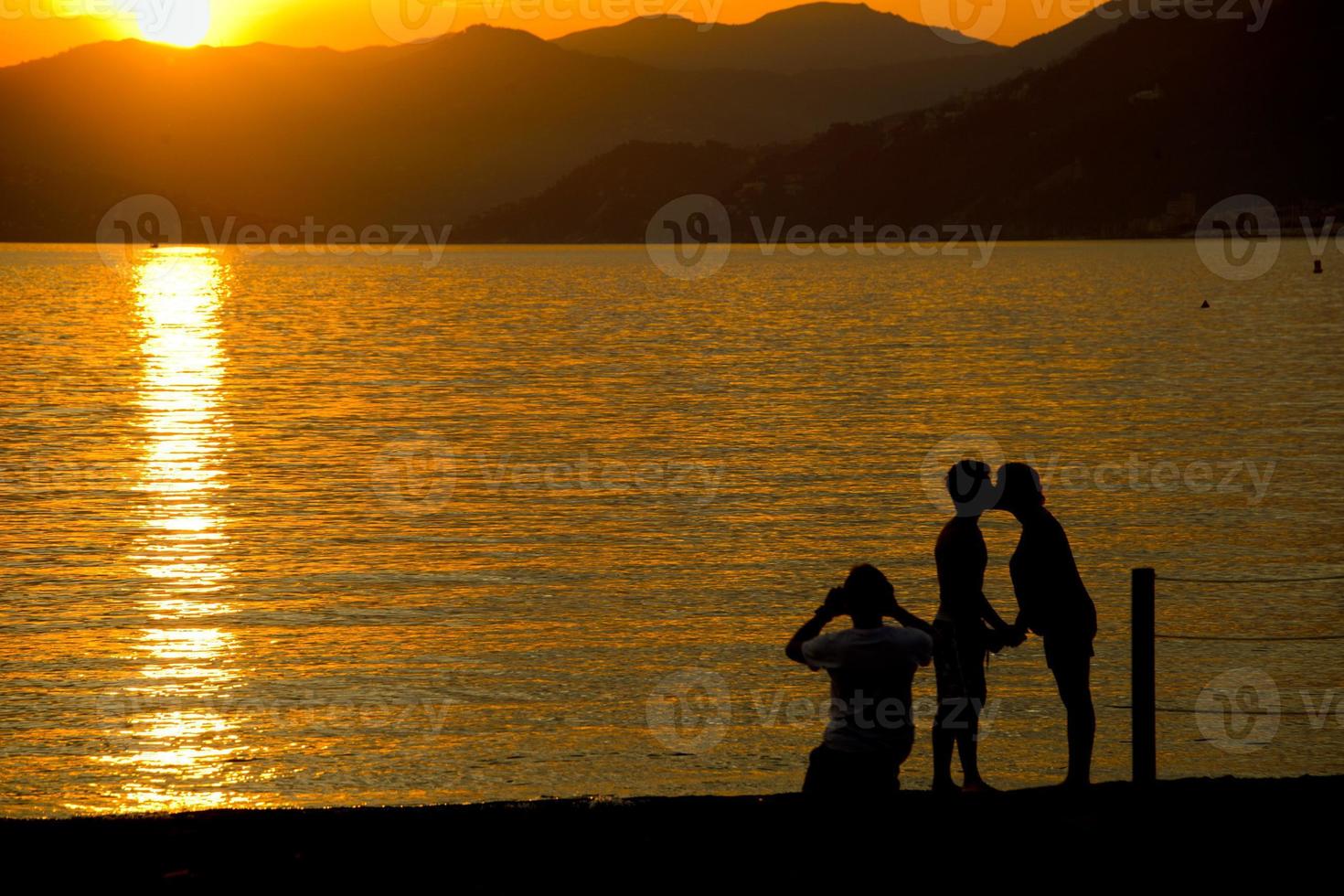 man and woman whiile kissing on sestri levante beach at sunset photo