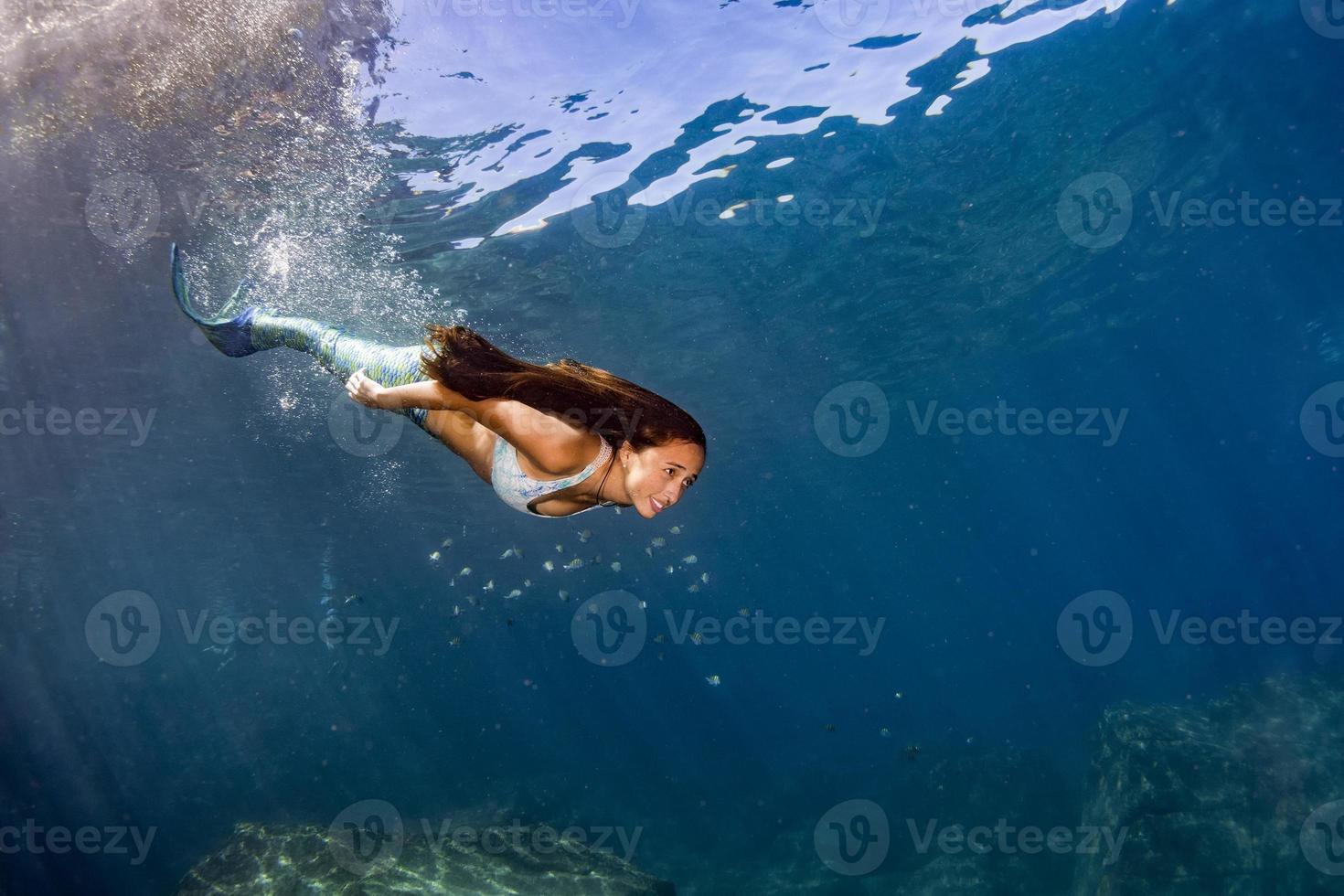 Mermaid swimming underwater in the deep blue sea photo