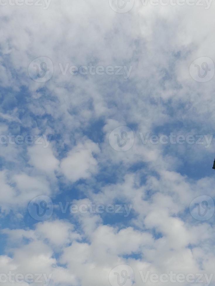 White clouds in the blue sky. Heaven and infinity. Beautiful bright blue background. Light cloudy, good weather. Curly clouds on a sunny day. photo