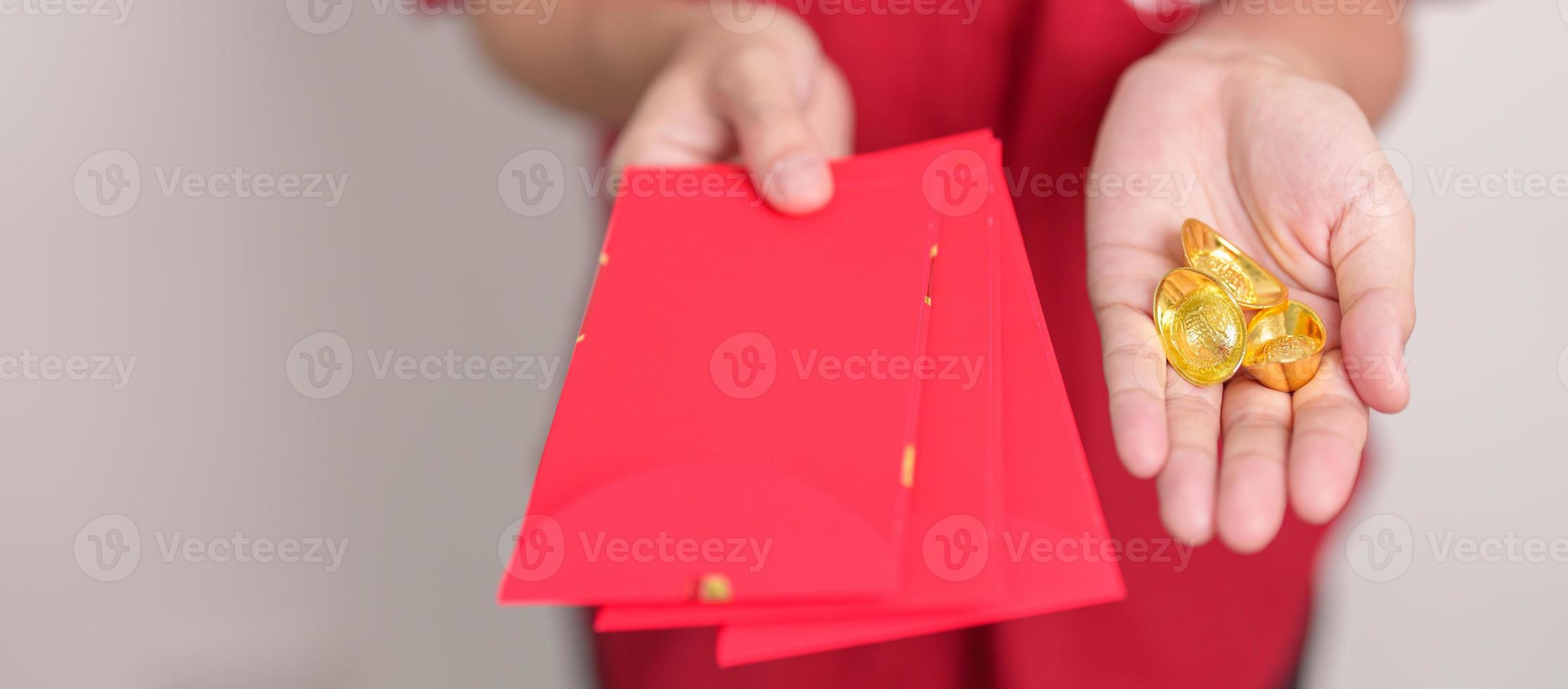 Woman holding Chinese red envelope with gold bullion, money gift for happy Lunar New Year holiday. Chinese sentence means happiness, healthy, Lucky and Wealthy photo