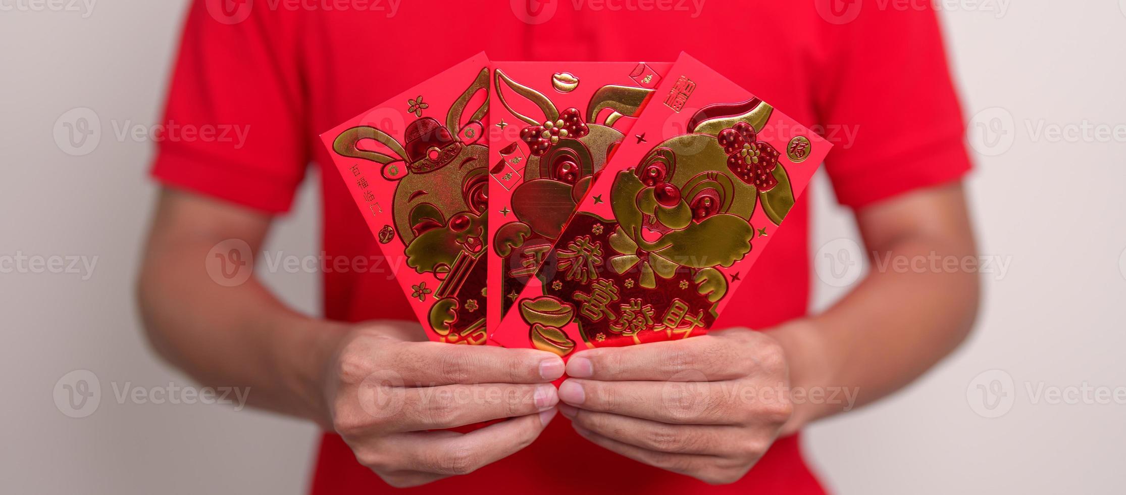 man holding Chinese red envelope with golden rabbit and blessing word, money gift for happy Lunar New Year holiday. Chinese sentence means happiness, healthy, Lucky and Wealthy photo