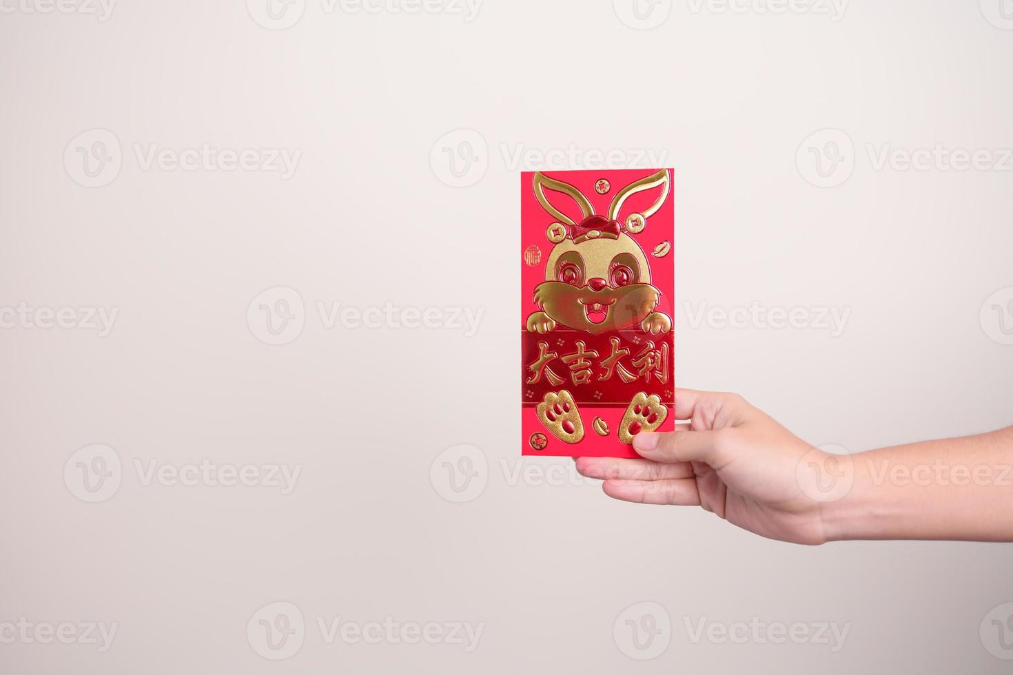mujer sosteniendo un sobre rojo chino con conejo dorado y palabra de bendición, regalo de dinero para felices vacaciones de año nuevo lunar. frase china significa felicidad, salud, suerte y riqueza foto