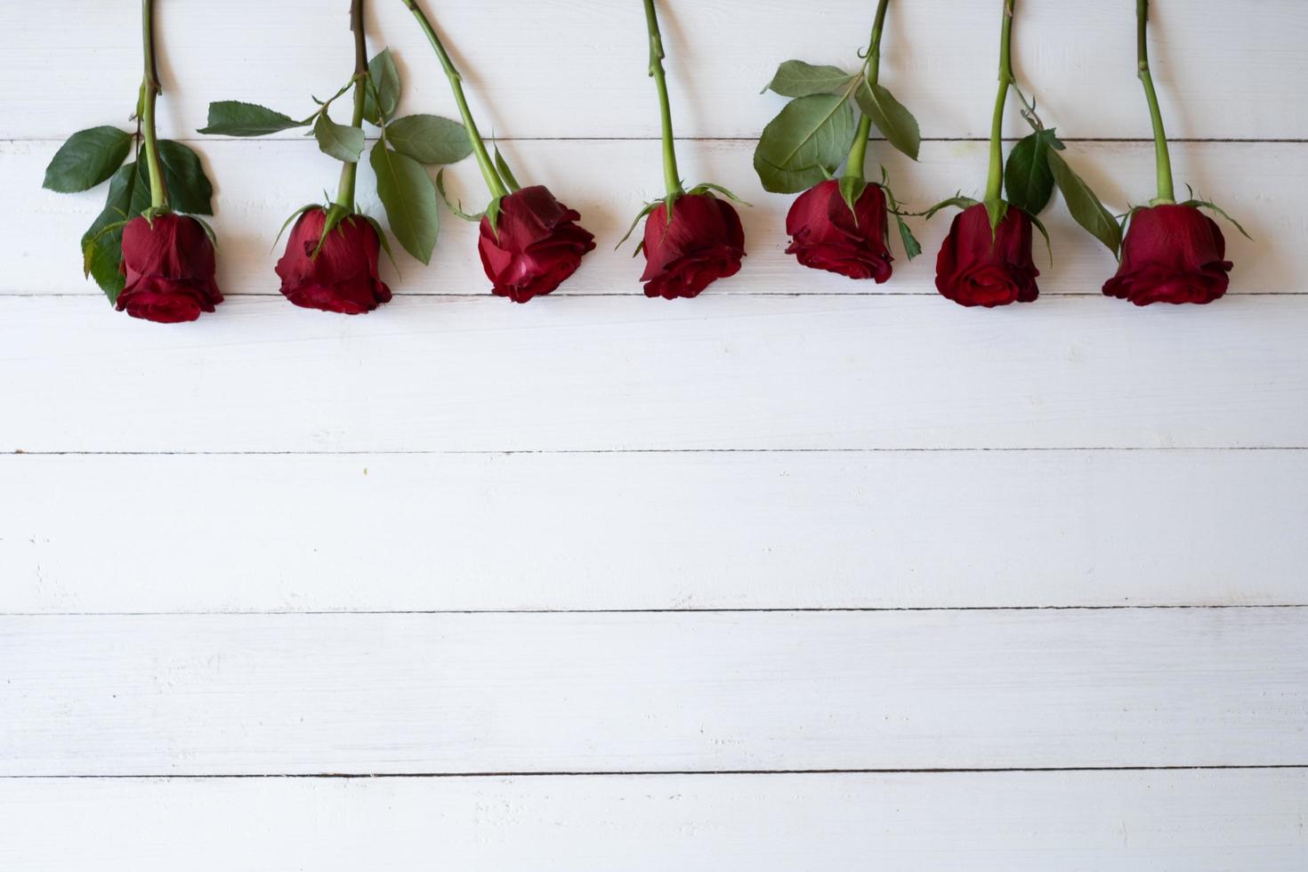 Border of red roses background. Beautiful fresh red roses symbolic of love and romance on wooden background for Valentine's day, wedding, birthday and special occasion concept. Copy space for text. photo