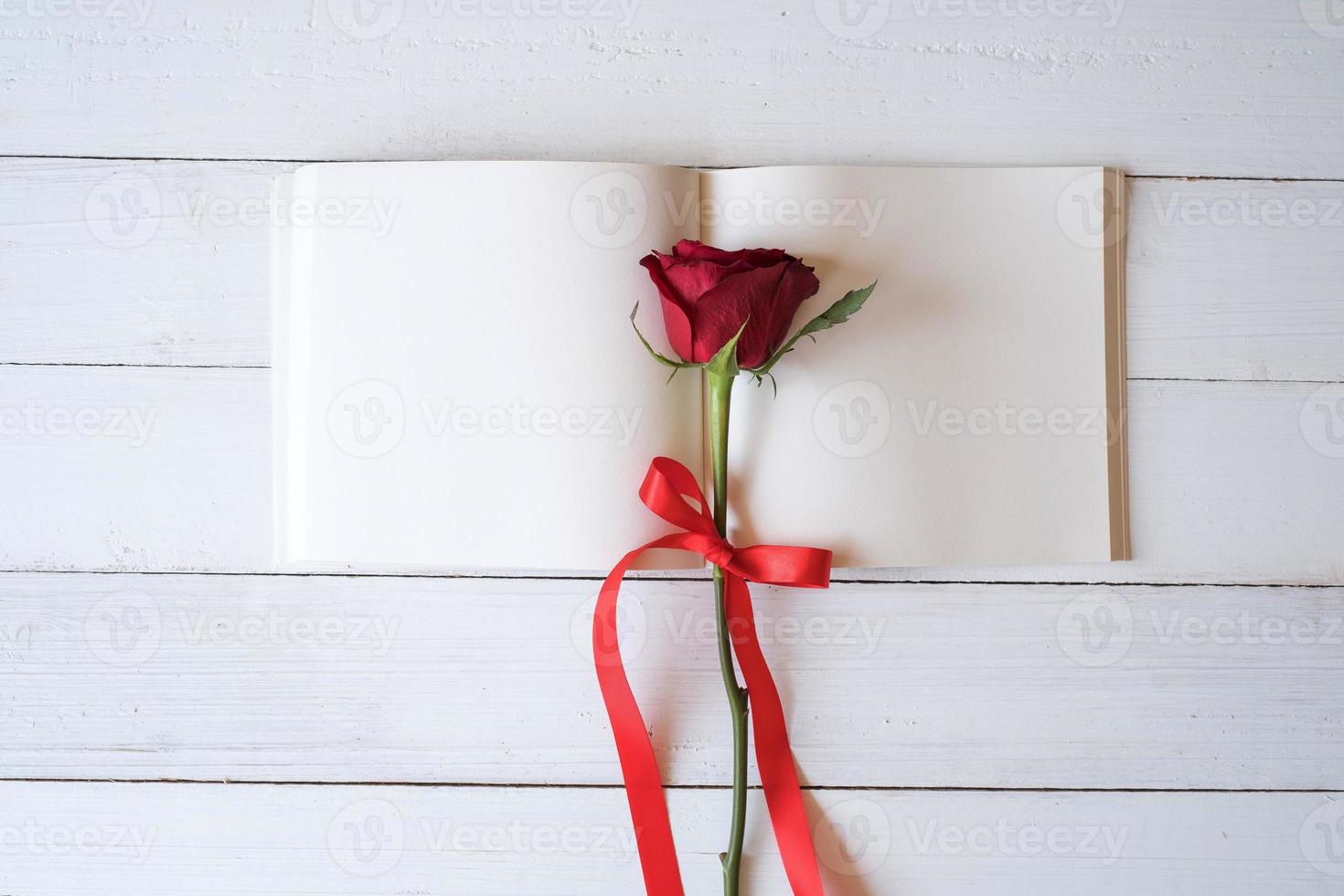 Blank notebook with red roses on wooden table. Copy space for your text. Valentine's day, wedding, birthday and special occasion concept. Copy space for text. Top view, Flat lay. photo