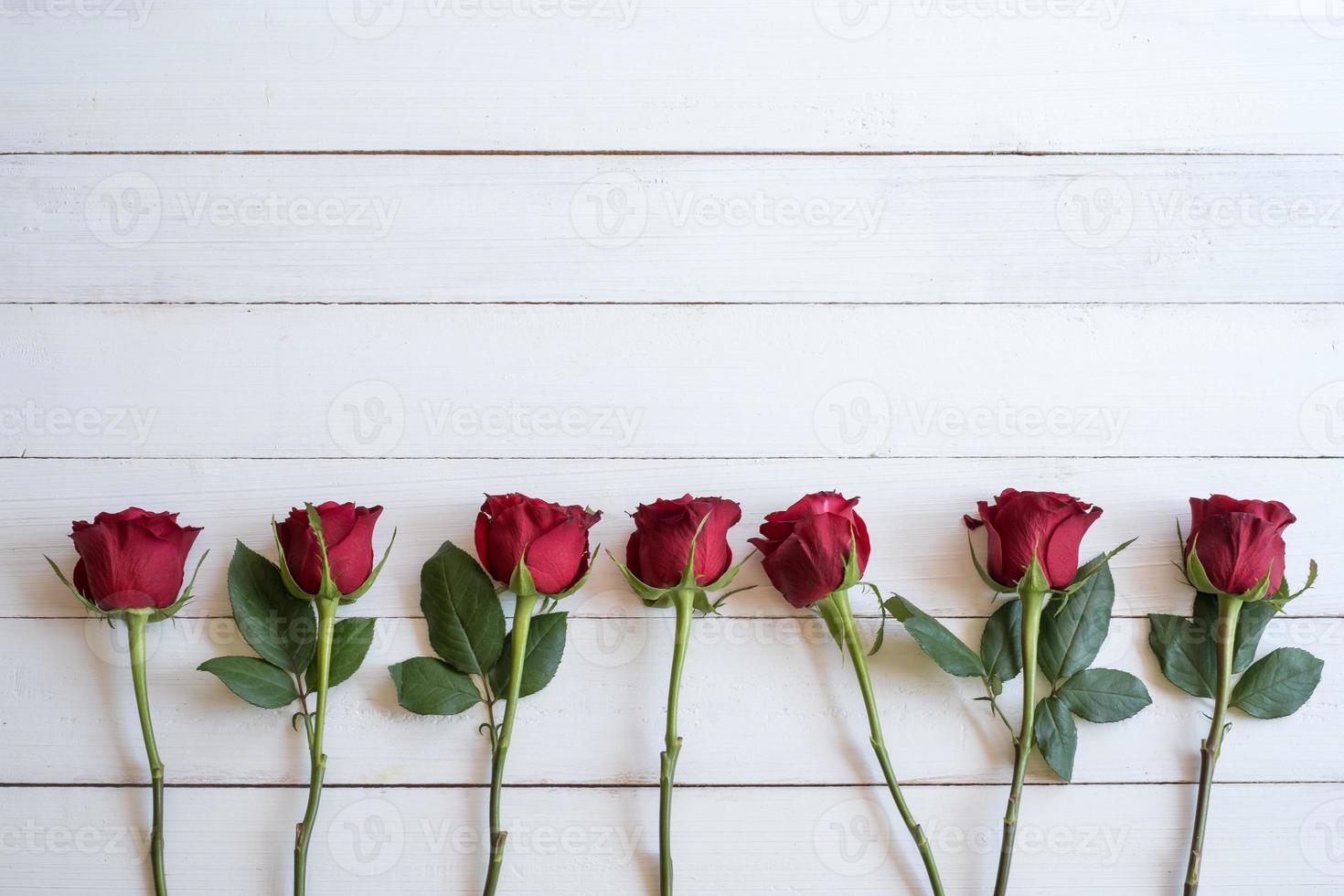 Border of red roses background. Beautiful fresh red roses symbolic of love and romance on wooden background for Valentine's day, wedding, birthday and special occasion concept. Copy space for text. photo