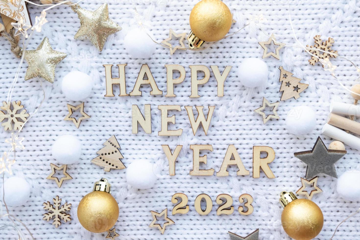 Happy New Year-wooden letters and the numbers 2023 on festive white knitted background with sequins, stars, lights of garlands. Greetings, postcard. Calendar, cover photo