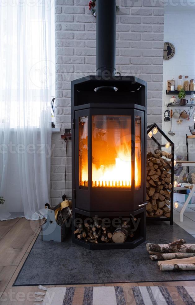 estufa negra, chimenea en el interior de la casa en estilo loft. calefacción ecológica alternativa, habitación cálida y acogedora en casa, madera quemada foto